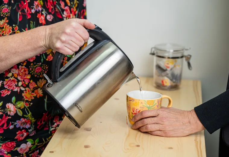 A person pouring from a kettle during a home assessment of everyday tasks