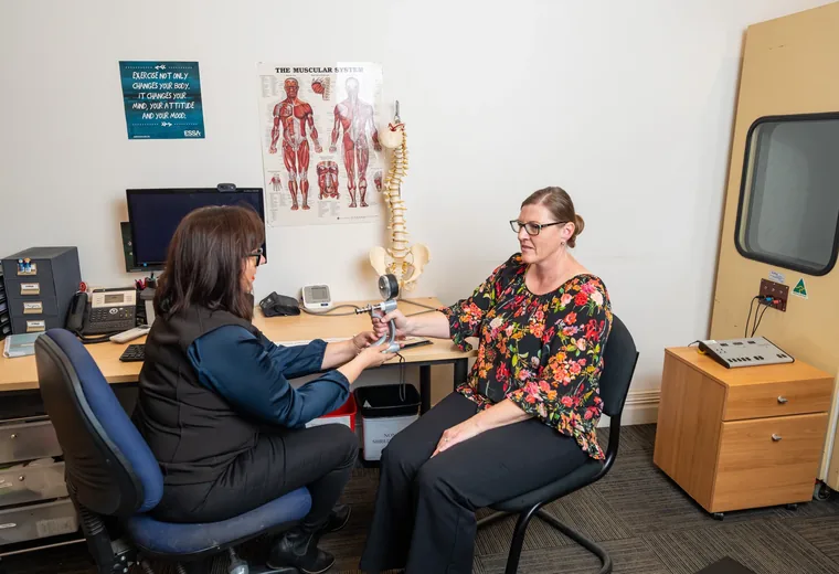 A Rehab Co clinician assessing a worker at their desk in the workplace