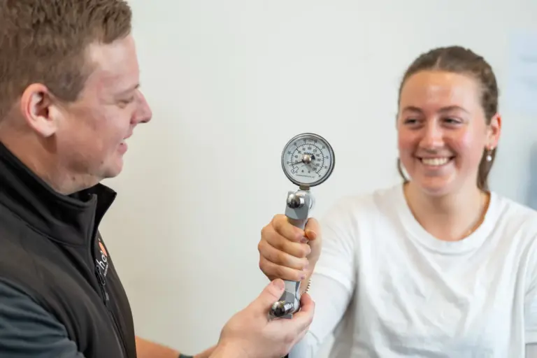 Rehab Co clinician measuring grip strength with a hand dynamometer