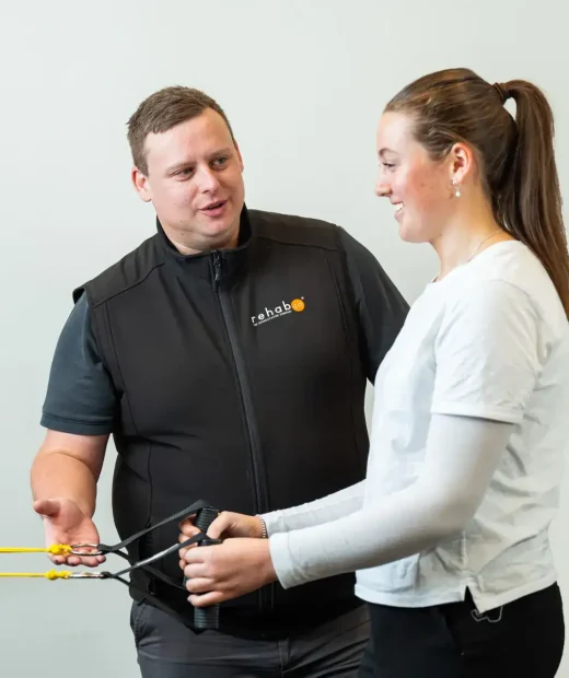 Rehab Co exercise physiologist guiding a client through resistance band exercises